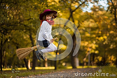 Funny little girl flies on broom in autumn Stock Photo