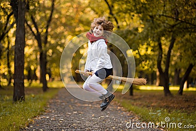 Funny little girl flies on broom in autumn Stock Photo