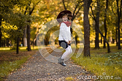 Funny little girl flies on broom in autumn Stock Photo