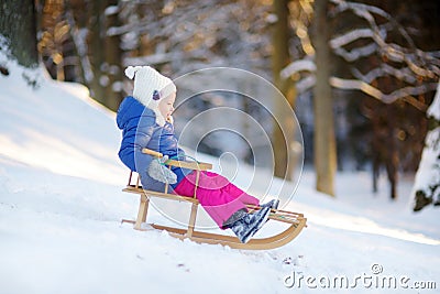 Funny little girl having fun with a sleight in winter park Stock Photo