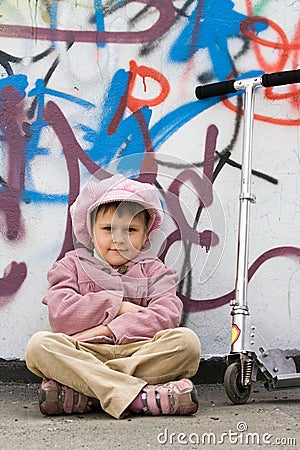 Funny little girl with scooter near graffiti wall Stock Photo