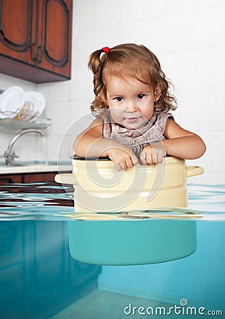 Funny little girl swim in pan in the flooded kitchen, rowdy crea Stock Photo