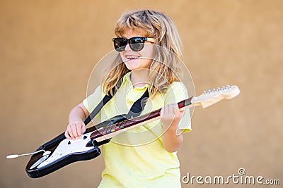 Funny little hipster musician child playing guitar. Portrait of a funny child with glasses practicing a song during a Stock Photo