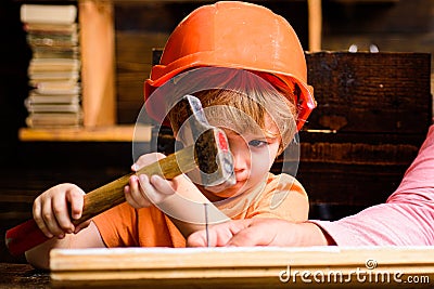 Funny little repairman with hammer. Kids construction worker. Child use a hammer to nail. Stock Photo