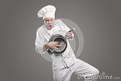 Expressive chef playing on colander like on guitar Stock Photo