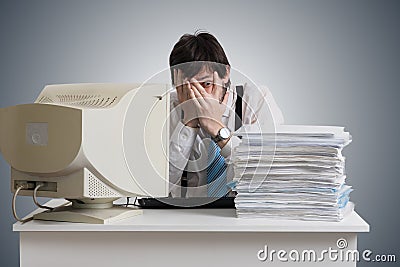 Funny man is covering face and looking on pile of documents on desk. Paperwork concept. Stock Photo