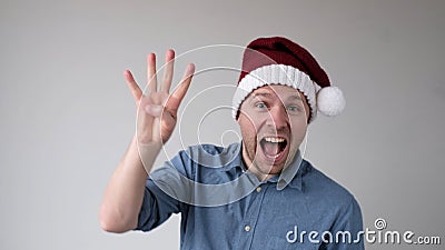 Funny Man in a New Year's Hat Counts Fingers, like Shows Numbers Stock Photo