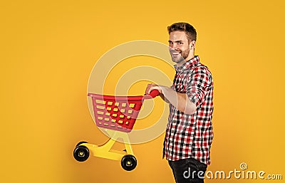 funny man with small shopping cart. weekend on buying products. rejoices successful purchases. spends money unwisely Stock Photo
