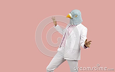 Funny man in a weird pigeon mask dancing and having fun at a crazy fancy dress party Stock Photo