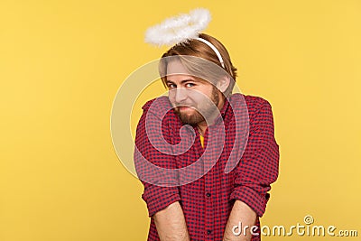 Funny modest cute bearded guy with saint nimbus over head looking at camera with shy timid expression Stock Photo