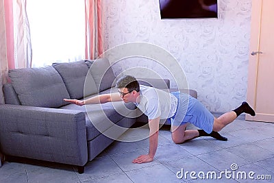 Funny nerd man is doing balance pose on all fours at home. Sport humor concept. Stock Photo
