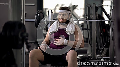 Funny overweight male stroking belly, exhausted after workout, insecurities Stock Photo