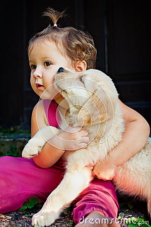 Funny photo of child cuddling beautiful golden labrador retriever puppy Stock Photo