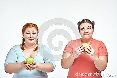 Chubby women: one woman is holding a sandwich,another one holding an apple Stock Photo