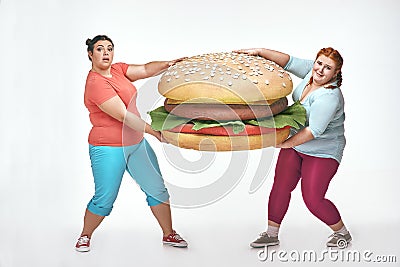 Two chubby women are holding a huge sandwich Stock Photo