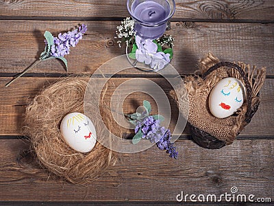 A funny picture for Easter, two eggs with painted faces. Basket and straw on which eggs sleep. Stock Photo