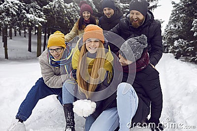 Funny and playful friends have fun playing with snow while walking in winter forest. Stock Photo