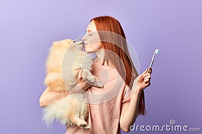 Funny pleasant ginger girl kissing with her adorable dog Stock Photo