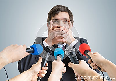 Funny politician is making no comment gesture. Many microphones in front Stock Photo