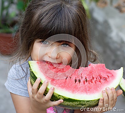 Funny portrait of an incredibly beautiful little girl blue eyes, eating watermelon, healthy fruit snack, Stock Photo