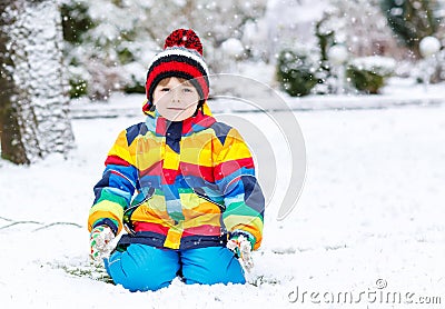 Funny preschool boy in colorful clothes happy about snow, outdoo Stock Photo
