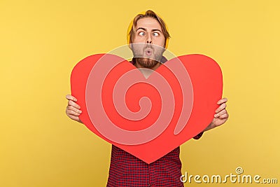 Funny romantic guy holding big read heart and looking at camera cross-eyed, having fun, demonstrating love Stock Photo