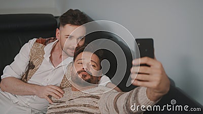 Funny romantic male gay couple using smartphone for video call. Stock Photo