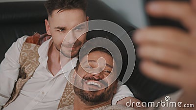 Funny romantic male gay couple using smartphone for video call. Stock Photo