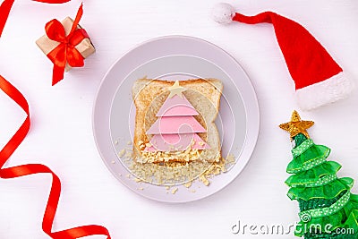 Funny sandwich with edible Christmas tree made from toast bread, sausage and cheese. Breakfast idea for kids. New Year Stock Photo