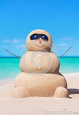 Funny sandy snowman in sunglasses at tropical sunny ocean beach. Stock Photo