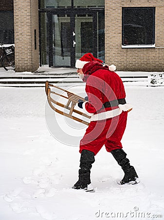 Christmas holiday time. Active Santa Claus with a sleigh joying in snow on a snowy street Stock Photo