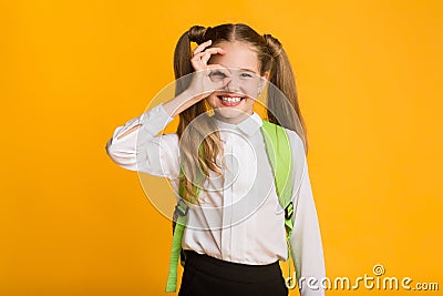 Funny Schoolgirl Gesturing Okay Sign Standing Over Yellow Background, Studio Stock Photo