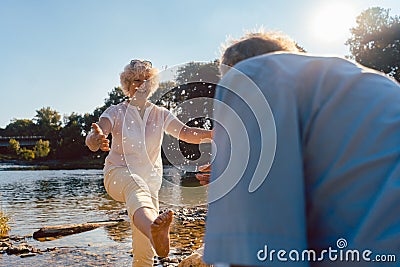 Funny senior couple playing with water at the river in a sunny day of summer Stock Photo