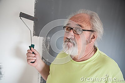 Funny senior man painting the wall Stock Photo
