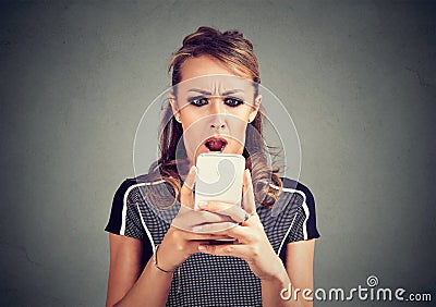 Funny shocked scared woman looking at phone seeing bad news photos message with disgusting emotion on face Stock Photo