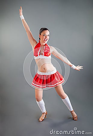 Funny slim brunette girl in red cheerleader costume poses at camera and smiles Stock Photo