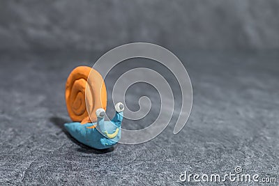 Funny snail made of play dough in front of grey background Stock Photo