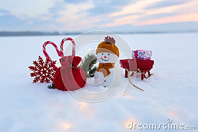 Funny snowman with sledges and colorful boxes with presents. Garlands enlighten the snow. New Year and Christmas concept with snow Stock Photo