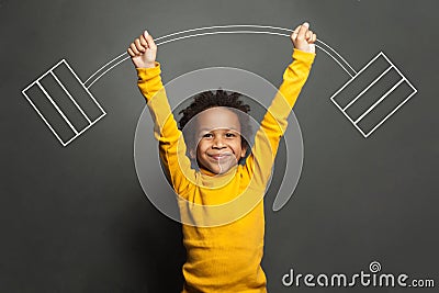Funny strong black kid with barbell in her hands on chalkboard background Stock Photo