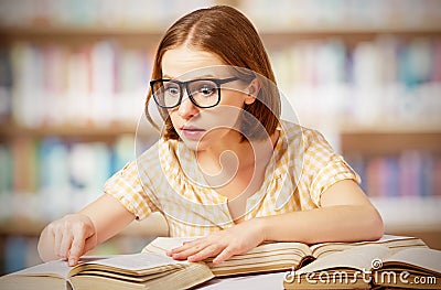 Funny surprised girl with glasses reading books Stock Photo
