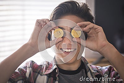 Funny teenager playing and joking with 2 bitcoins on his eyes - future payment and money concept Stock Photo