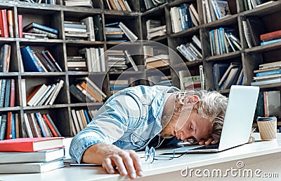 Funny tired sleepy university student sleeping sitting at library desk. Stock Photo