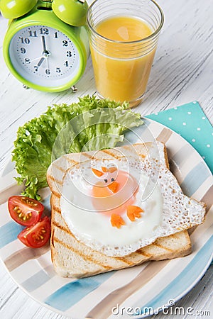 Funny toast with fried egg in a shape of chicken and alarm clock, food for kids Easter idea Stock Photo