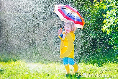 Funny toddler with umbrella playing in the rain Stock Photo