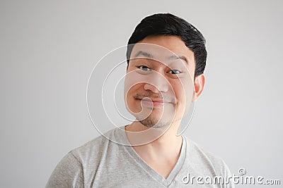 Funny tricky awkward smirk face of man in grey t-shirt Stock Photo