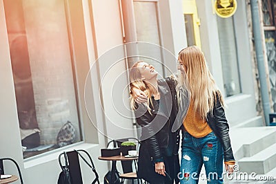 It is funny walk with best friend! Two beautiful women walking outdoor hugging and laughing on autumn street. Stock Photo