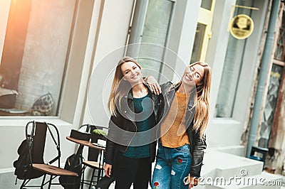 It is funny walk with best friend! Two beautiful women walking outdoor hugging and laughing on autumn street. Stock Photo