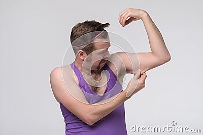 Funny weak sportsman exercising looking on his biceps Stock Photo