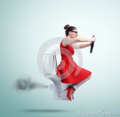 Funny woman in red flying on the toilet with steering wheel. Concept of movement Stock Photo