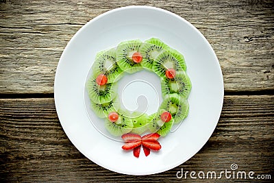 Funny xmas food idea for kids - kiwi strawberry edible Christmas wreath Stock Photo